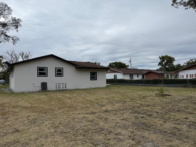 rear view of house with cooling unit and a yard