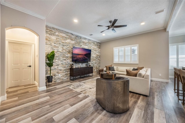 living room with ceiling fan, wood-type flooring, a textured ceiling, and ornamental molding