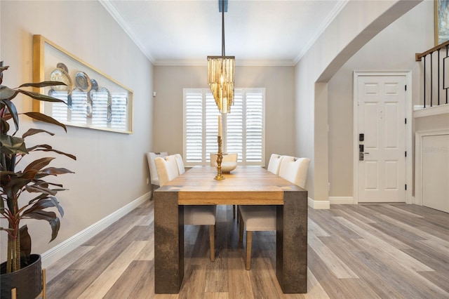 dining room with a chandelier, crown molding, and light hardwood / wood-style flooring