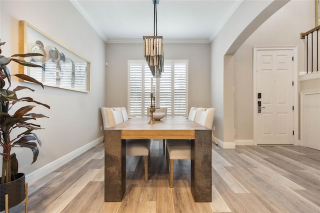 dining area with ornamental molding and light hardwood / wood-style flooring