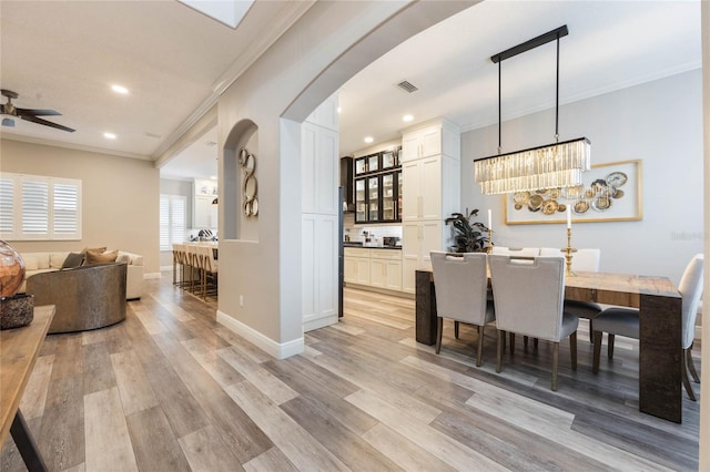 dining area featuring ceiling fan, light wood-type flooring, and ornamental molding