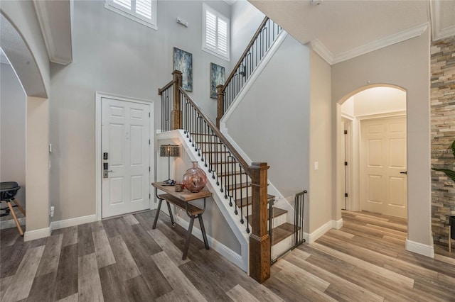 foyer featuring ornamental molding, a towering ceiling, and hardwood / wood-style flooring