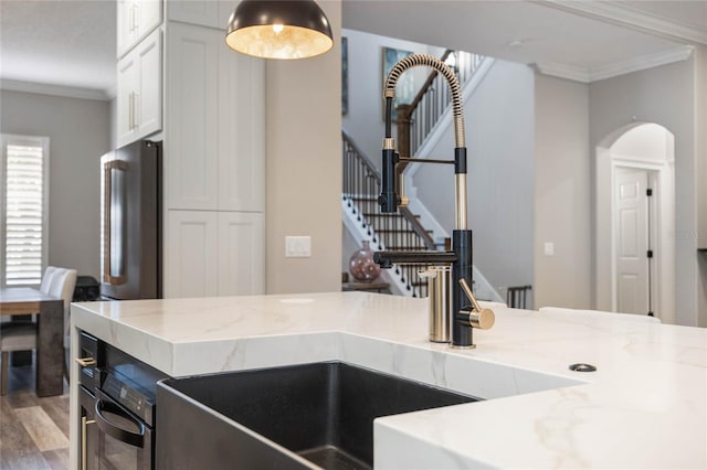 kitchen featuring light stone countertops, white cabinets, ornamental molding, and high end refrigerator