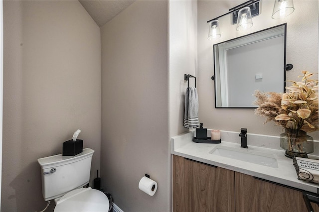 bathroom featuring lofted ceiling, vanity, and toilet