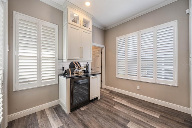 bar with dark wood-type flooring, beverage cooler, white cabinets, and crown molding