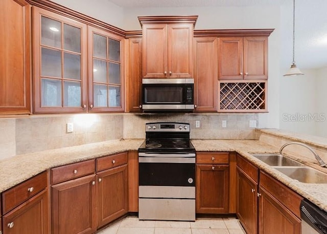 kitchen featuring stainless steel appliances, sink, light tile patterned floors, hanging light fixtures, and light stone countertops