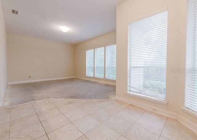 spare room featuring a textured ceiling and light tile patterned floors