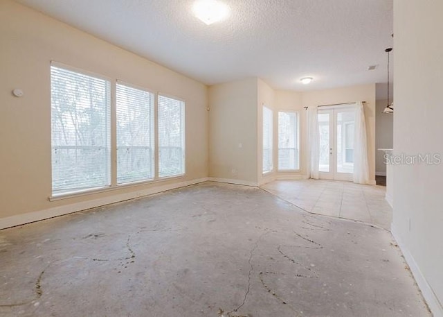 empty room with a textured ceiling and french doors