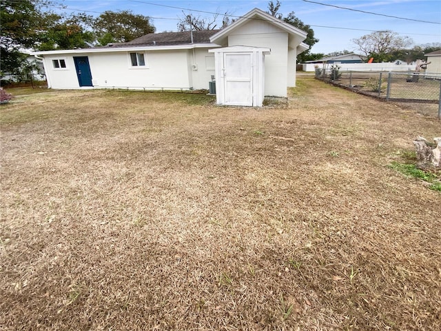 rear view of house featuring cooling unit and a yard