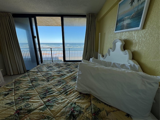 bedroom with multiple windows, expansive windows, access to outside, and a water view