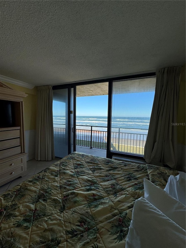 bedroom featuring tile patterned floors, floor to ceiling windows, access to outside, a textured ceiling, and a water view