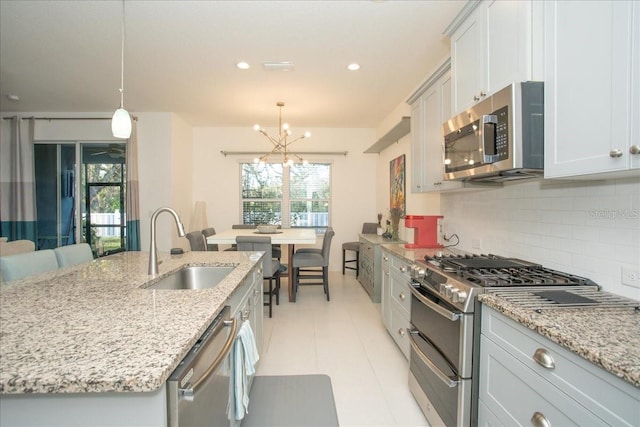 kitchen with pendant lighting, appliances with stainless steel finishes, sink, and tasteful backsplash