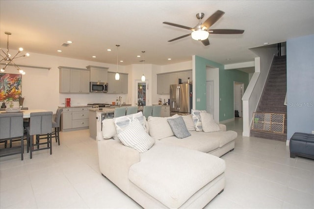 tiled living room with sink and ceiling fan with notable chandelier