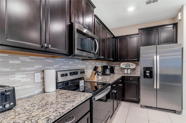 kitchen with appliances with stainless steel finishes, backsplash, and light stone countertops