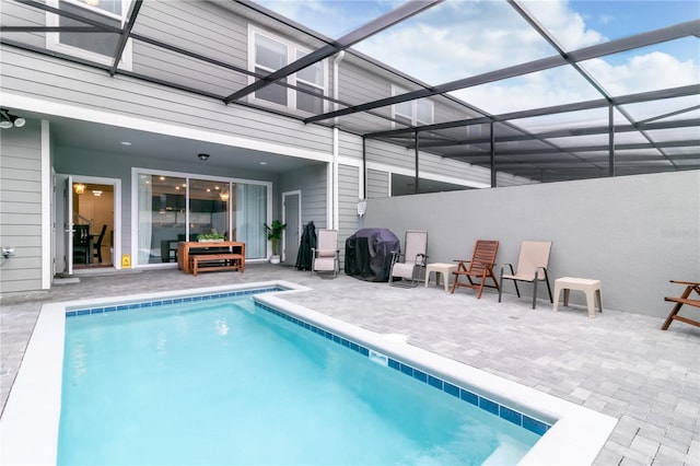 view of swimming pool featuring grilling area, a patio area, and glass enclosure