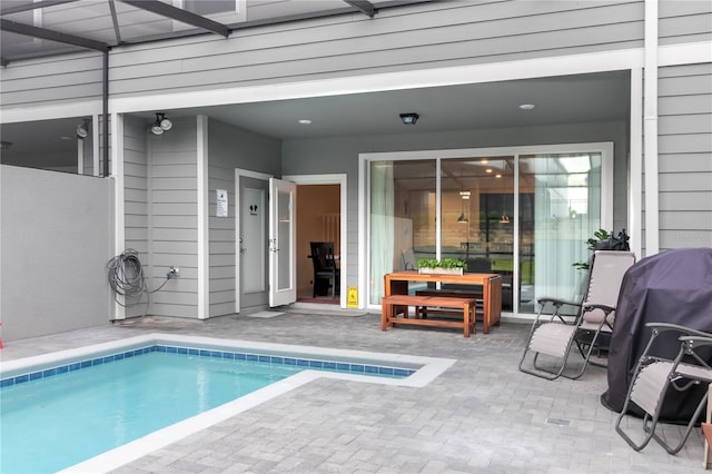 view of pool with glass enclosure, a patio, and grilling area