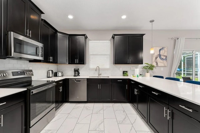 kitchen featuring decorative backsplash, sink, hanging light fixtures, and stainless steel appliances