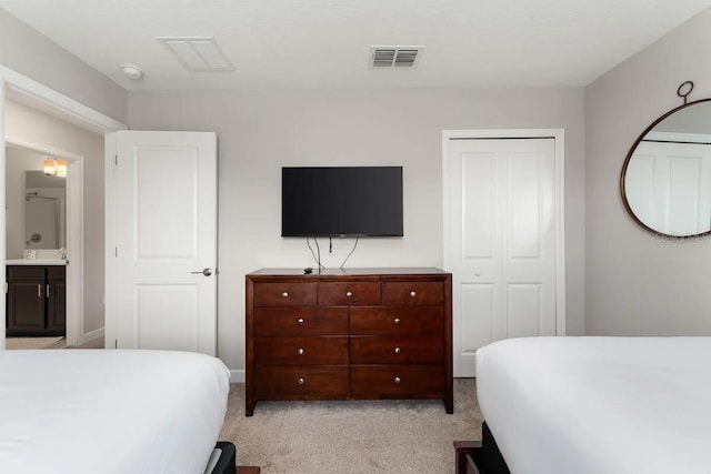 bedroom with light colored carpet, ensuite bathroom, and sink