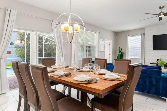 dining area featuring ceiling fan with notable chandelier, a healthy amount of sunlight, and wooden walls