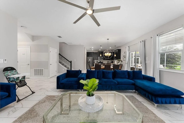 living room with ceiling fan with notable chandelier