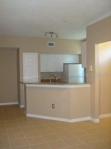 kitchen with white cabinetry, refrigerator, and kitchen peninsula