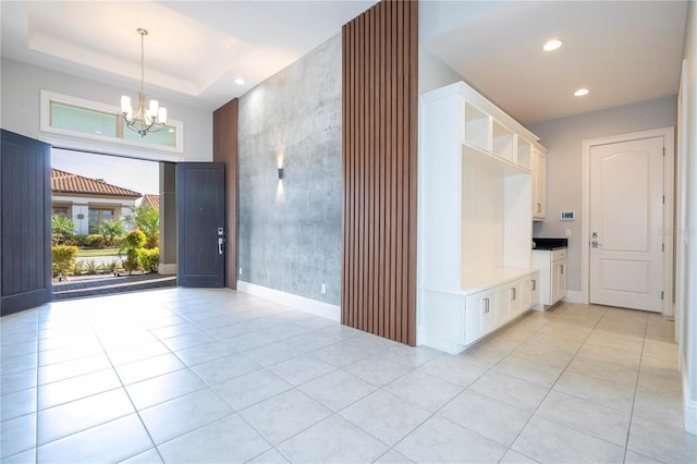 tiled entrance foyer with an inviting chandelier, a tray ceiling, and a towering ceiling