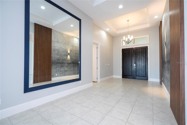 entryway featuring an inviting chandelier, a towering ceiling, a raised ceiling, and light tile patterned flooring