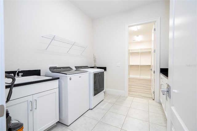 washroom with sink, light tile patterned floors, cabinets, and washer and dryer