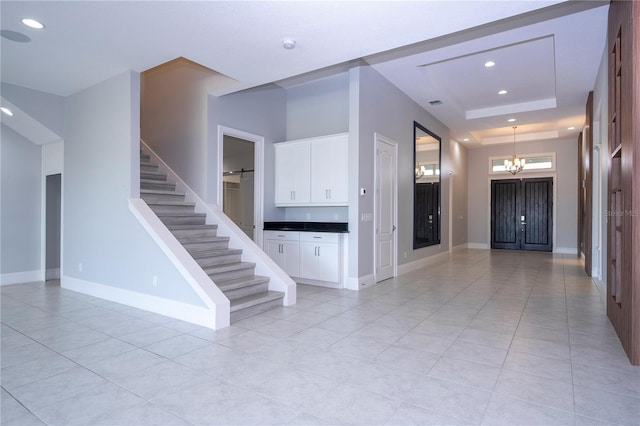 staircase featuring a chandelier, a raised ceiling, and tile patterned floors