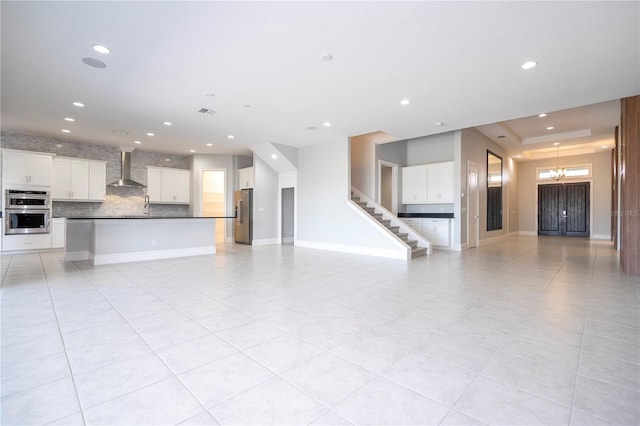 unfurnished living room featuring light tile patterned flooring, a tray ceiling, and sink