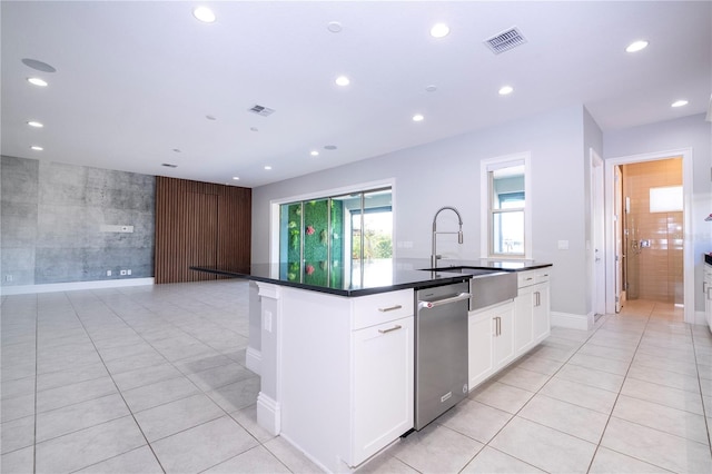 kitchen with sink, light tile patterned floors, dishwasher, a kitchen island with sink, and white cabinets