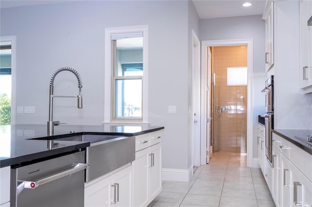 kitchen featuring stainless steel appliances, white cabinetry, sink, and light tile patterned flooring