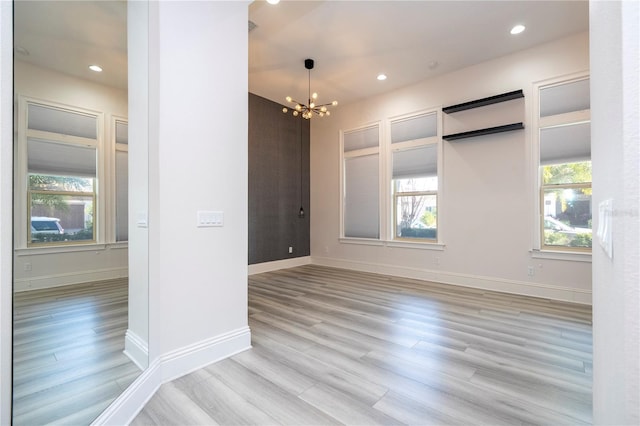 empty room with a notable chandelier and light hardwood / wood-style flooring