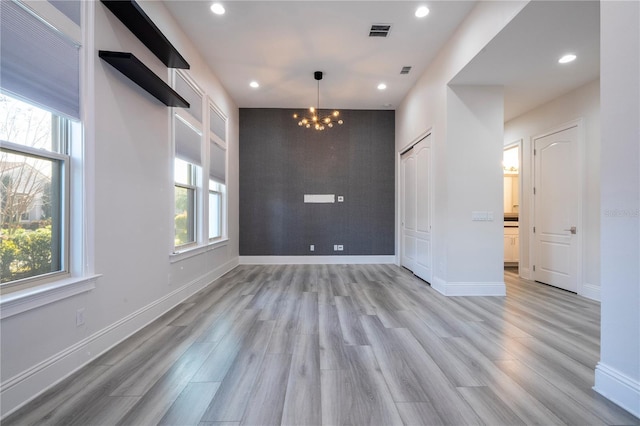 spare room featuring a chandelier and light hardwood / wood-style flooring