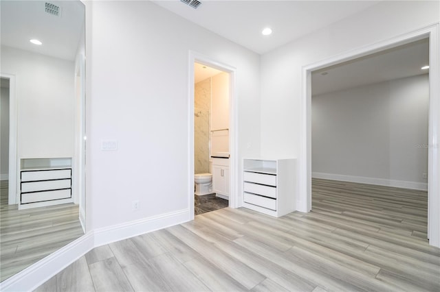 unfurnished bedroom featuring connected bathroom and light wood-type flooring