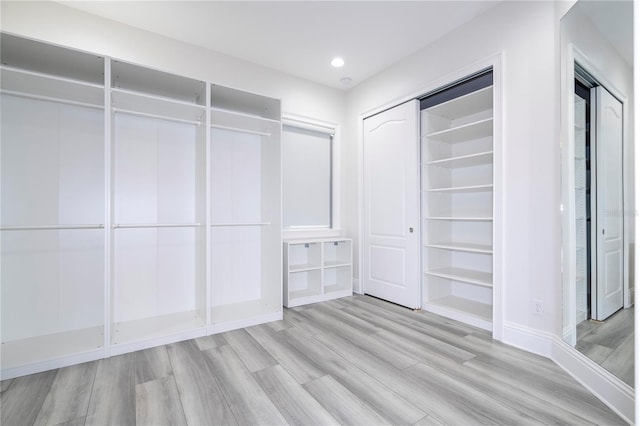 walk in closet with light hardwood / wood-style flooring