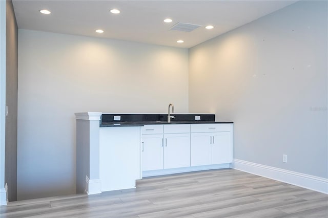 bar with sink, white cabinets, and light wood-type flooring