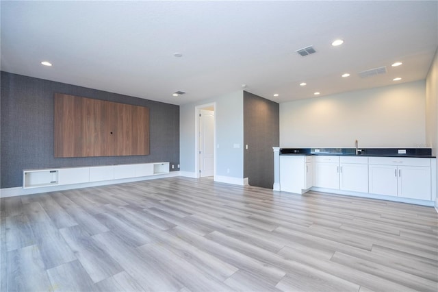 unfurnished living room featuring sink and light hardwood / wood-style floors