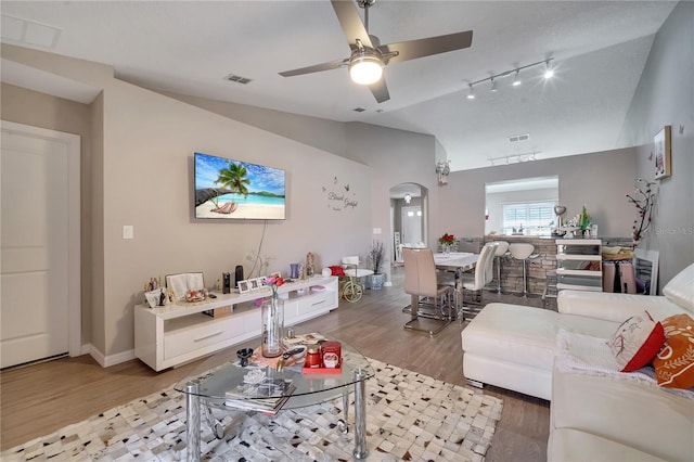 living room with lofted ceiling, hardwood / wood-style flooring, rail lighting, ceiling fan, and a textured ceiling