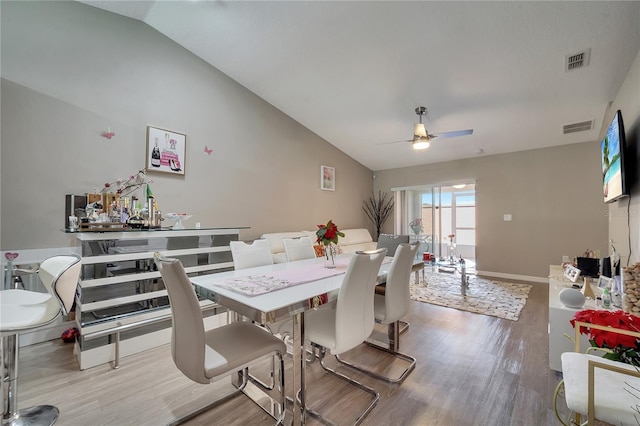 dining room with vaulted ceiling, wood-type flooring, and ceiling fan