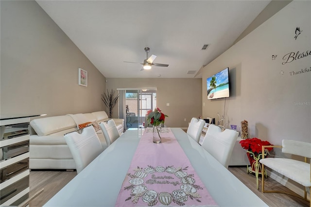 dining area featuring ceiling fan, lofted ceiling, and light hardwood / wood-style flooring