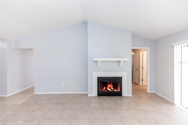 unfurnished living room with light tile patterned floors, baseboards, vaulted ceiling, and a tiled fireplace