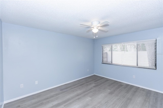 spare room featuring ceiling fan, a textured ceiling, baseboards, and wood finished floors