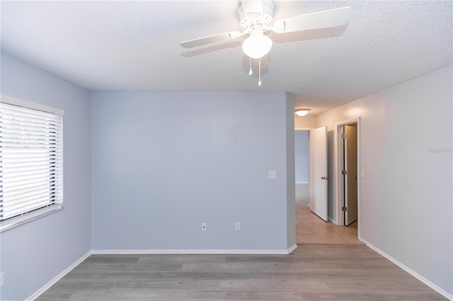 empty room featuring a ceiling fan, a textured ceiling, baseboards, and wood finished floors