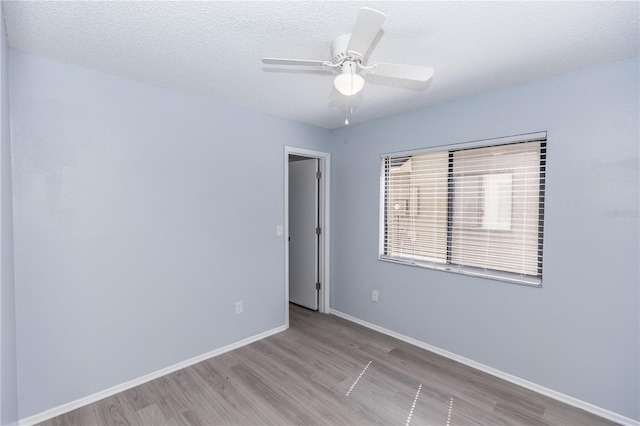 spare room featuring ceiling fan, a textured ceiling, wood finished floors, and baseboards