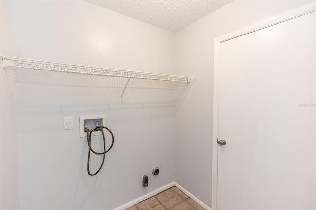 clothes washing area with washer hookup, laundry area, a textured ceiling, and light tile patterned floors