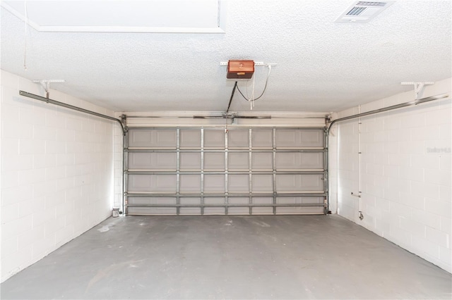 garage featuring concrete block wall, visible vents, and a garage door opener