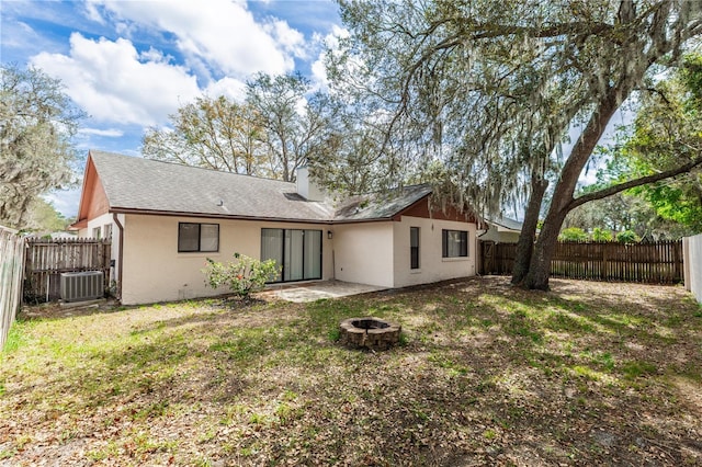 back of house featuring an outdoor fire pit, stucco siding, a fenced backyard, and central air condition unit