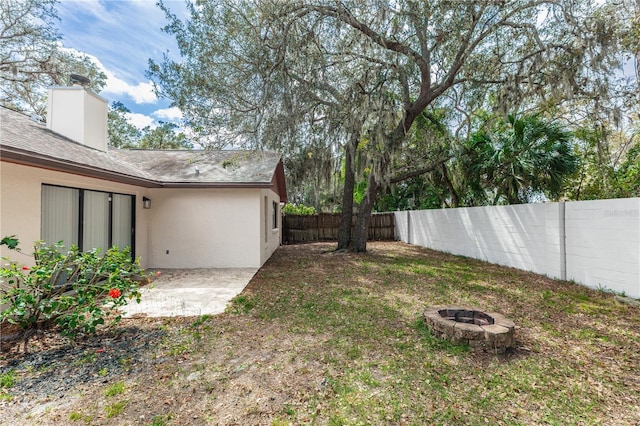 view of yard featuring a fenced backyard, a patio, and a fire pit