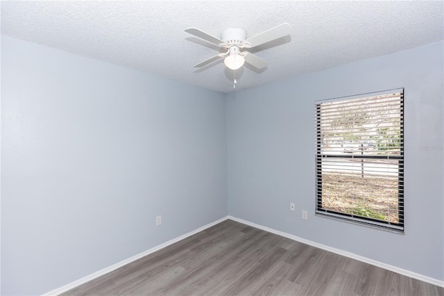 empty room featuring a textured ceiling, ceiling fan, wood finished floors, and baseboards